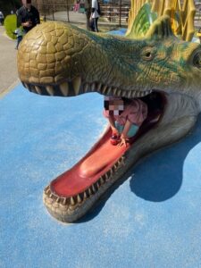岡崎東公園のスピノザウルスの口から顔を出す子ども